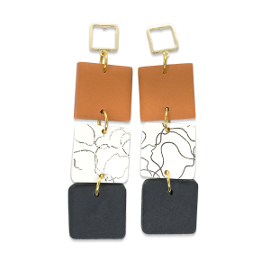 Contemporary cube shaped dangly earring in terracotta patterned white and black and textured black. With cubed gold stud